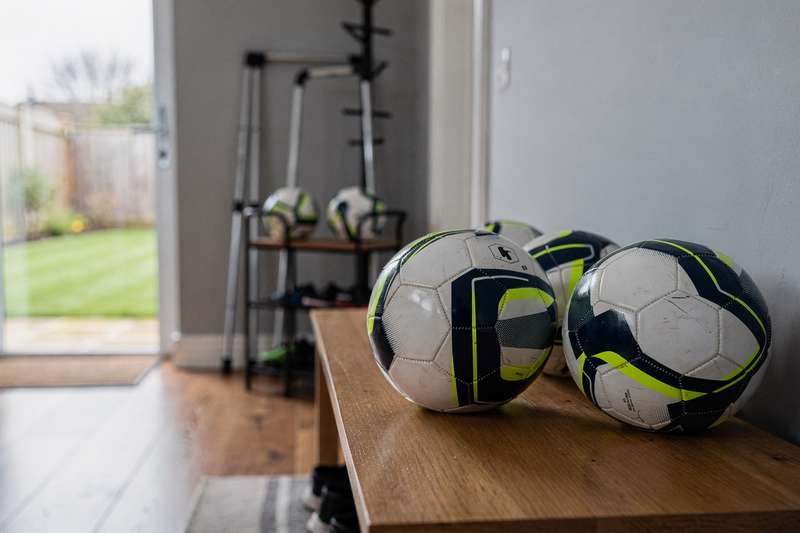 Spieler treten mit dem Fuß gegen einen Fußball auf einem grünen Rasenplatz während eines Trainings.