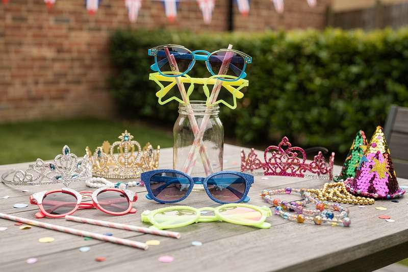 Frau mit bunter Party-Brille und Glitzermaske lacht fröhlich auf einer festlichen Feier.