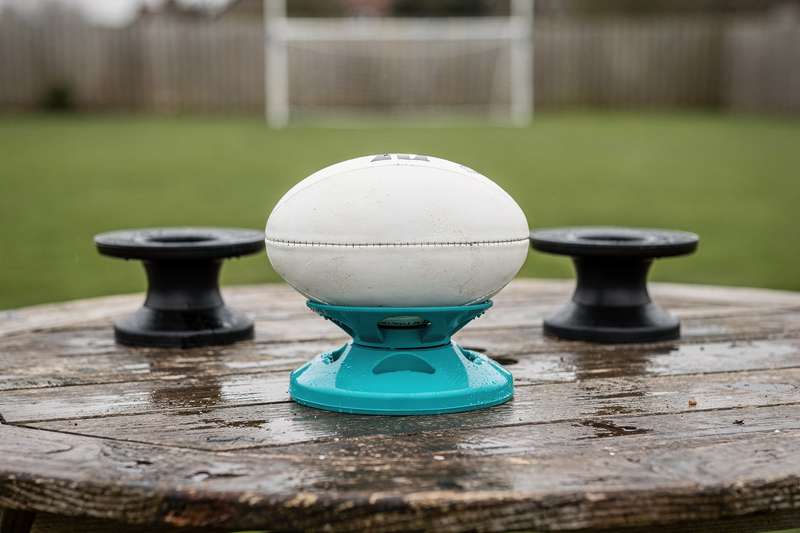 Rugbyspieler positioniert einen Ball auf einem Kicking-Tee vor dem Tor zum Schussversuch.